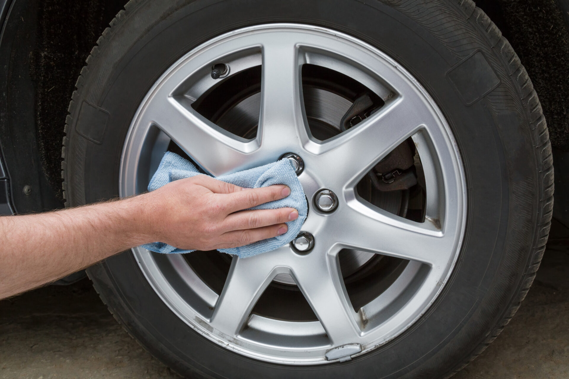 Man's,Hand,With,Rag,Cleaning,A,Dusty,Car,Wheel,Disk